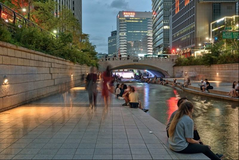 Pessoas na margem do riacho urbanizado de Cheonggyecheon, em Seul, capital da Coreia do Sul. Desde sua inaugura